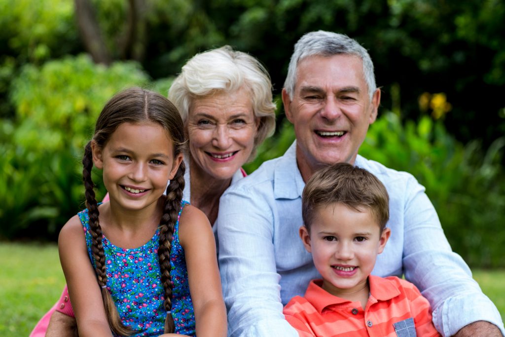 Smiling grandparents with grandchildren at yard